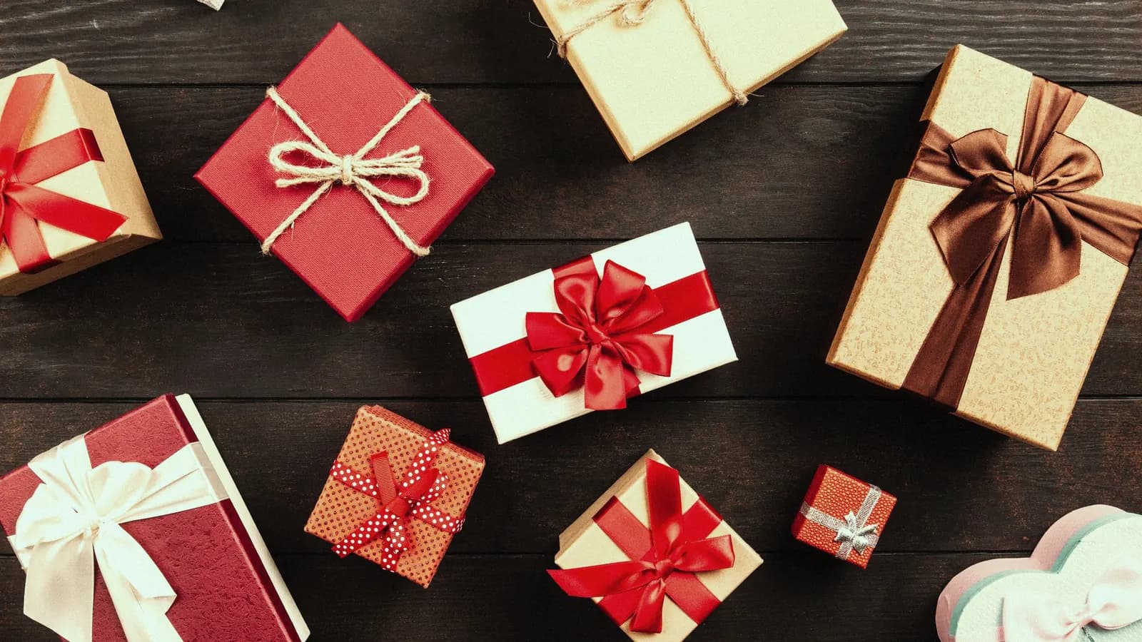 Wrapped presents with red and gold ribbons on a wooden table.