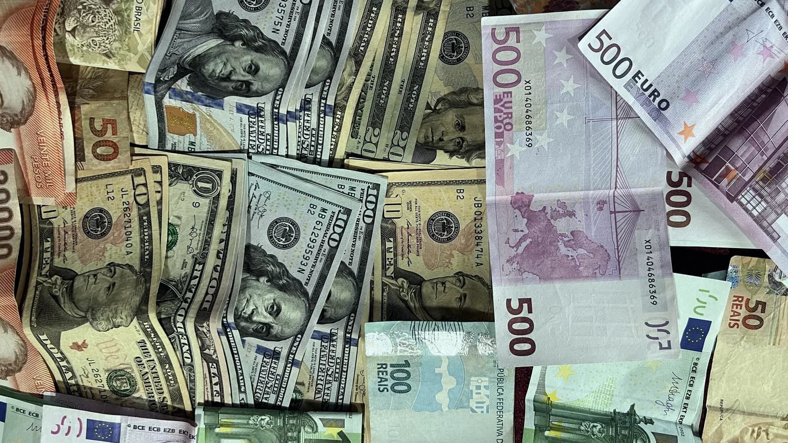 A pile of banknotes in several currencies, including US dollars and euros.