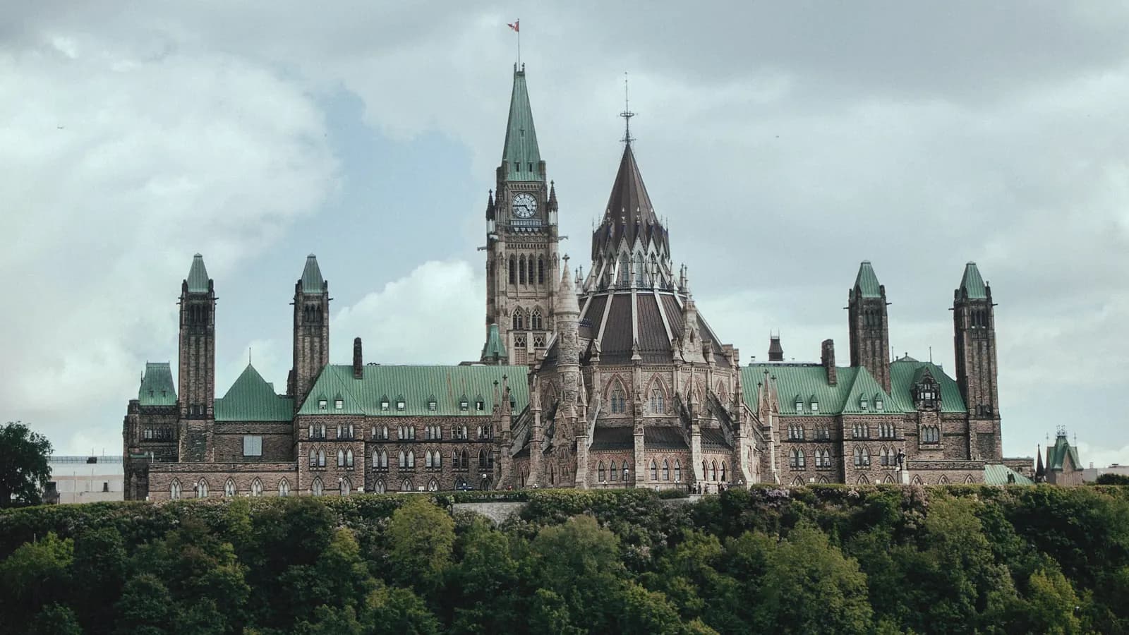 The Parliament buildings on Parliament Hill in Ottawa, above the trees along the river.