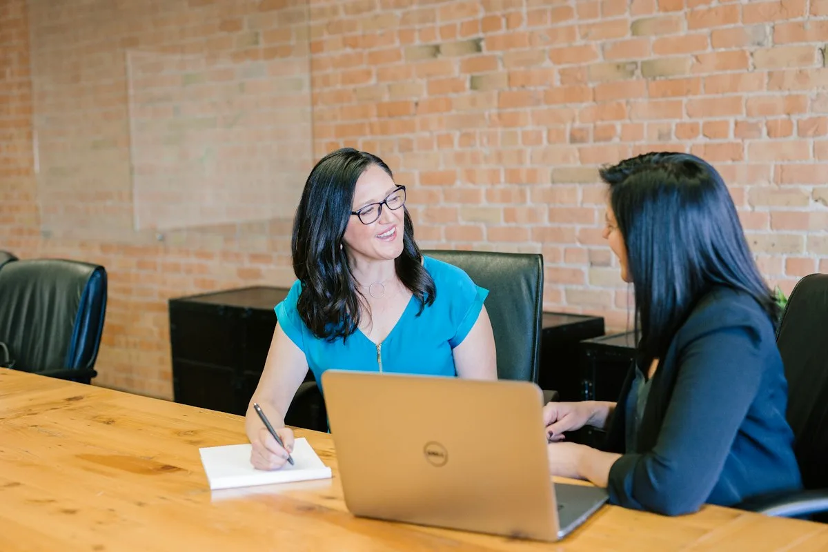A freelancer working at a desk with a laptop, notebooks, and expense receipts.