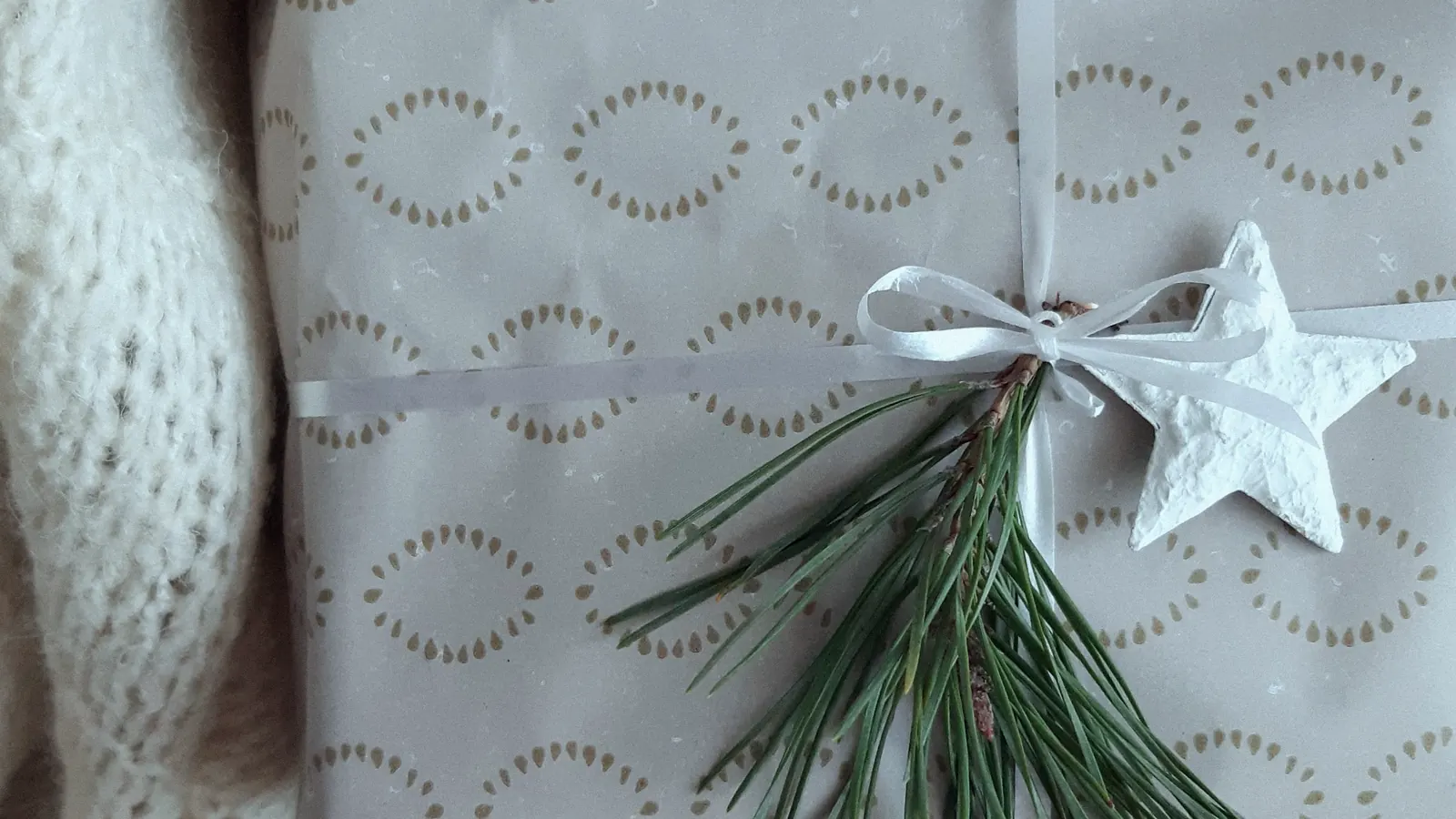 A wrapped gift tied with ribbon, a pine sprig and a paper star.