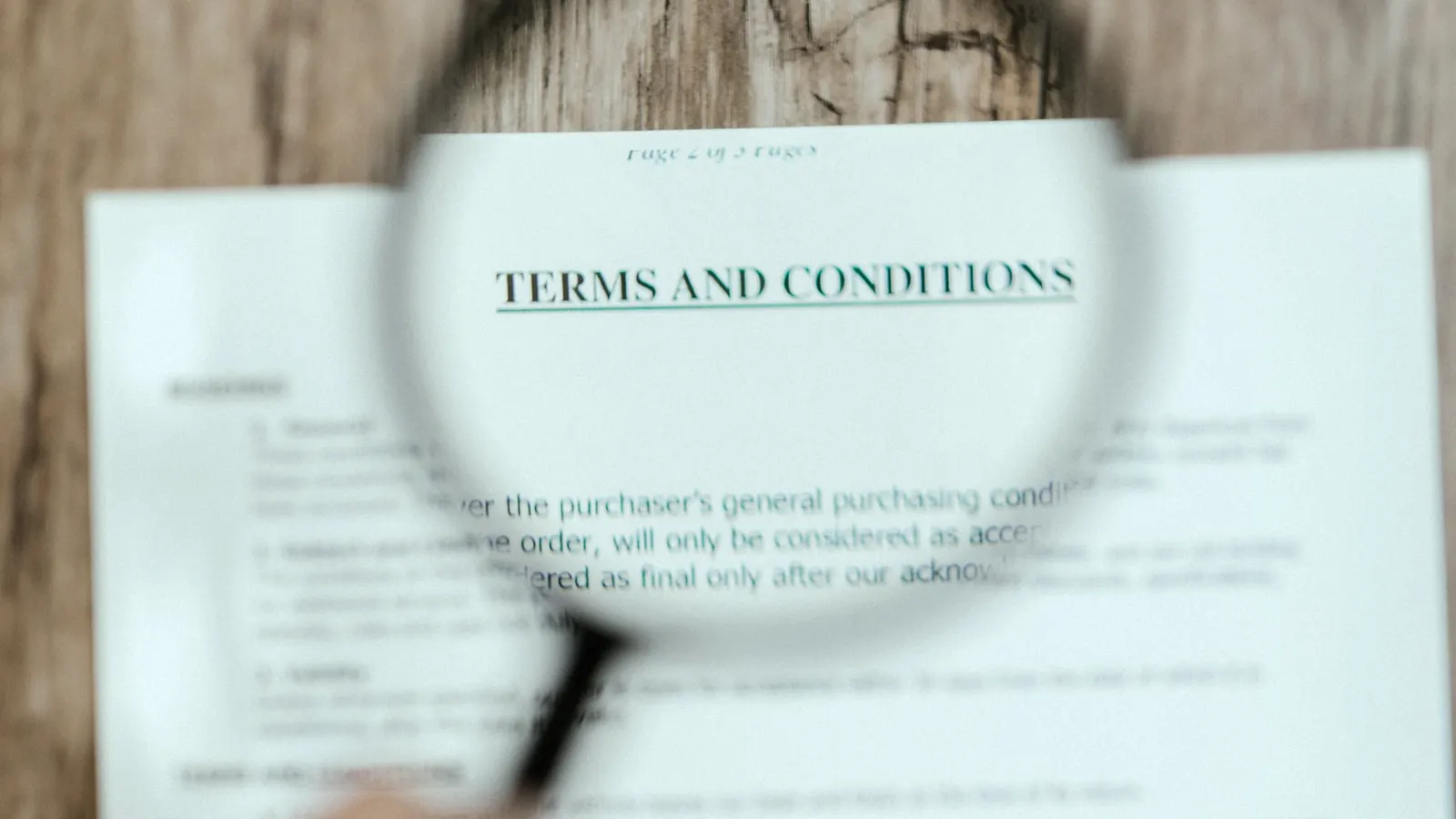 A magnifying glass held over the terms and conditions heading of a printed warranty document.