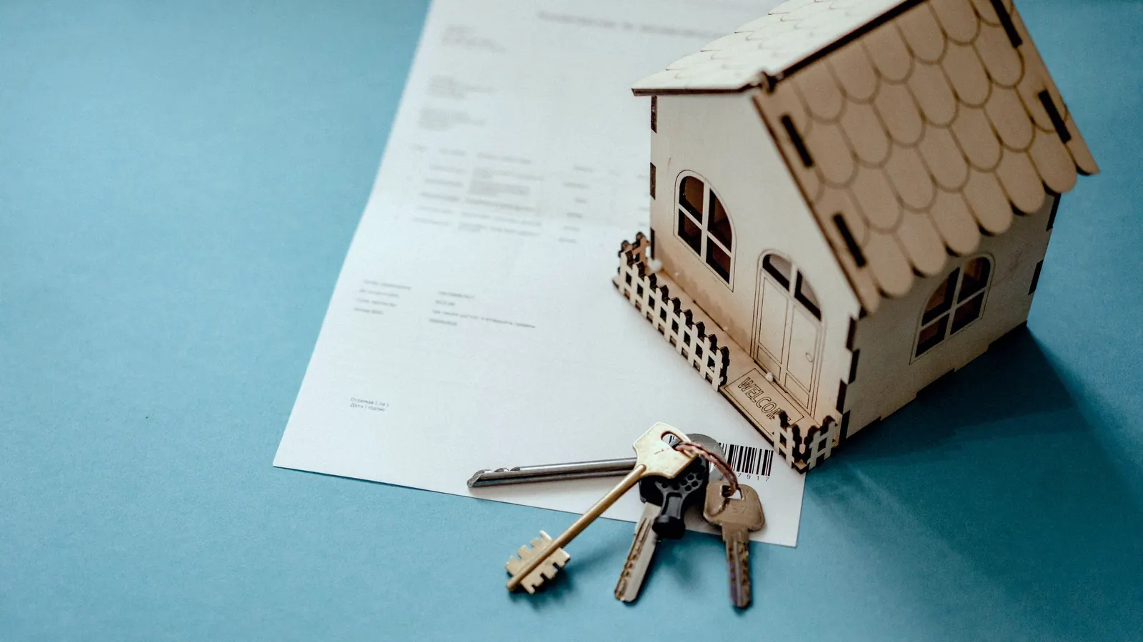 House keys and a model house resting on a rental contract.