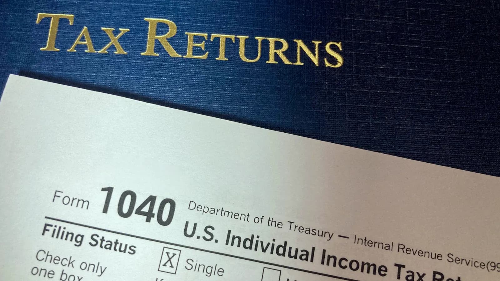 A Form 1040 U.S. Individual Income Tax Return tucked into a folder marked Tax Returns.